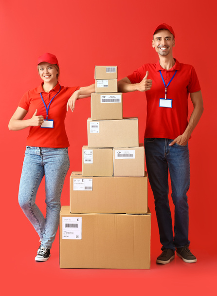 Couriers with many parcels on color background - Фото, изображение