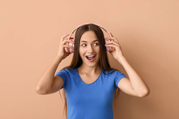 Cool young woman listening to music on color background - Fotó, kép