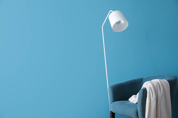 White floor lamp and armchair near blue wall - Фото, зображення