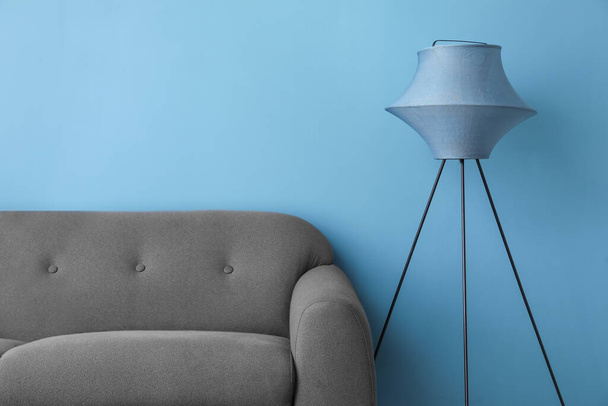 Tyylikäs standardi lamppu ja sohva lähellä sinistä seinää - Valokuva, kuva