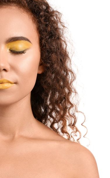 Hermosa mujer afroamericana con maquillaje en tonos amarillos sobre fondo blanco - Foto, Imagen