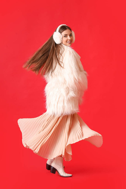 Ευτυχισμένη νεαρή γυναίκα σε ζεστά χειμωνιάτικα ρούχα στο φόντο χρώμα - Φωτογραφία, εικόνα