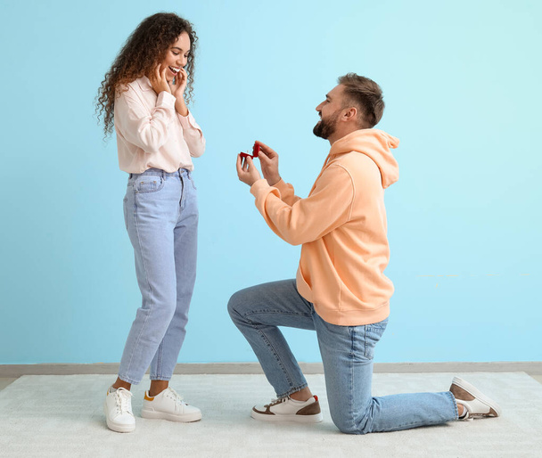 Young man proposing to his girlfriend on color background - Valokuva, kuva