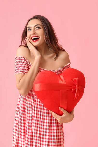 Beautiful young woman with red heart on pink background. Valentine's Day celebration - Foto, afbeelding