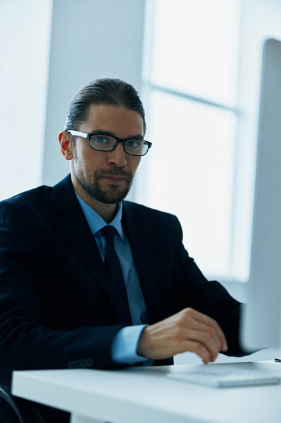 business man in a suit with glasses in the office at his desk - Φωτογραφία, εικόνα