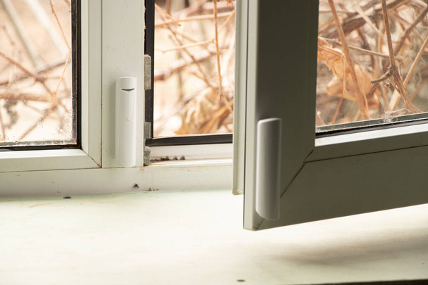sensor de apertura de ventana colgado en la ventana, sistema de alarma para el hogar, protección del hogar, alarma para el hogar - Foto, Imagen