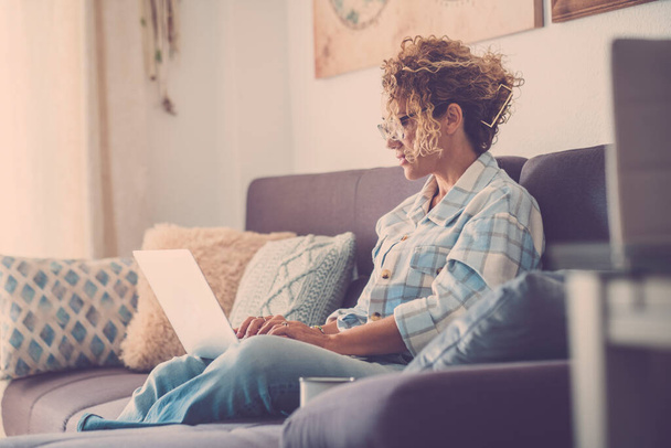 ενήλικη γυναίκα φορώντας γυαλιά εργασίας με φορητό υπολογιστή στο άνετο σπίτι - Φωτογραφία, εικόνα