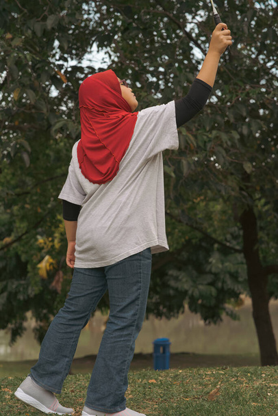 Young hijab Asian girl playing badminton at the park. - Fotoğraf, Görsel