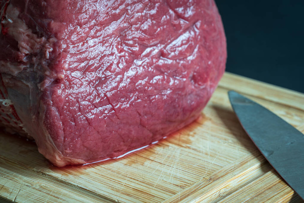 Roh gebratenes Rindfleisch auf einem Holzschneidebrett in Großaufnahme - Foto, Bild