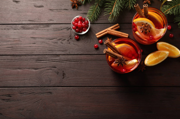 Delicious punch drink with cranberries, orange and spices on wooden table. flat lay. Space for text - Foto, imagen