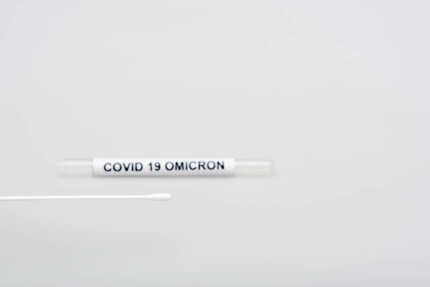 swab test near blurred covid-19 omicron test tube on grey background - Foto, afbeelding