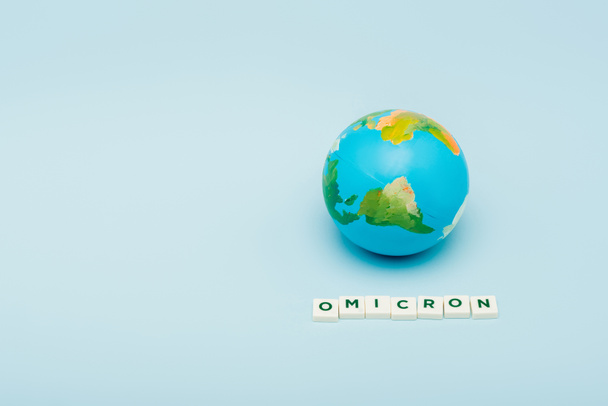 white cubes with omicron lettering near globe on blue background with copy space - Photo, image