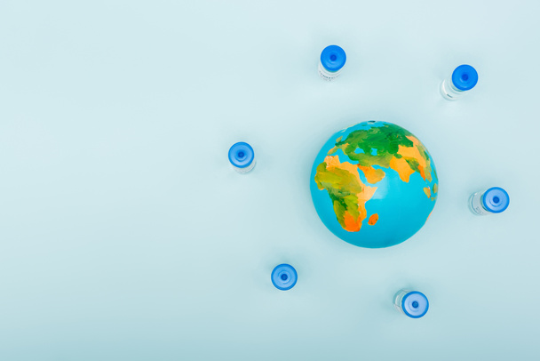 top view of vaccine bottles near globe on blue background with copy space - Zdjęcie, obraz