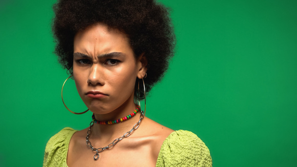 frustrated african american woman frowning and looking at camera isolated on green - Photo, Image