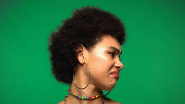δυσαρεστημένη Αφροαμερικανή που κοιτάζει μακριά, απομονωμένη στο πράσινο.  - Φωτογραφία, εικόνα