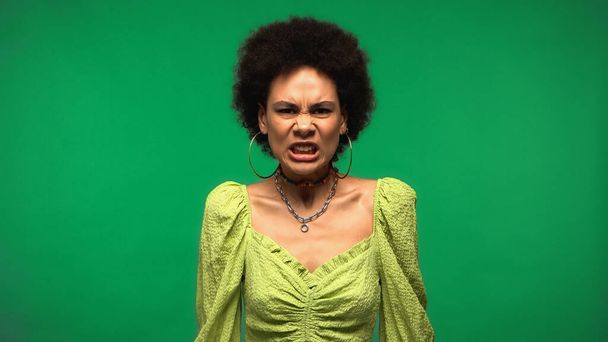 furiosa mujer afroamericana mirando la cámara aislada en verde - Foto, Imagen