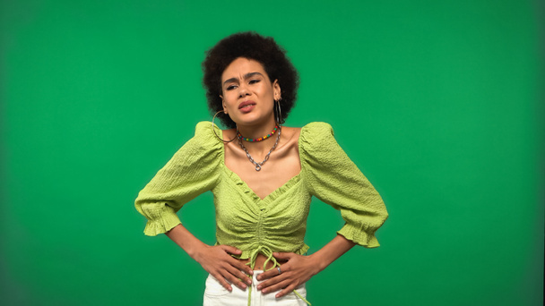 mujer afroamericana insatisfecha en pendientes de aro con dolor de estómago aislado en verde  - Foto, imagen