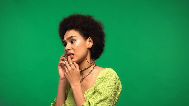 worried african american woman in blouse talking on cellphone isolated on green - Photo, Image
