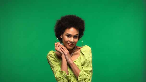 joyful african american woman in blouse and hoop earrings isolated on green  - Valokuva, kuva