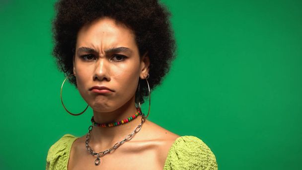 frusztrált afro-amerikai nő blúzban és karika fülbevaló elszigetelt zöld  - Fotó, kép