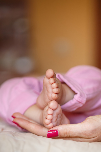 τα πόδια του νεογέννητου σε ήπια τα χέρια της μητέρας - Φωτογραφία, εικόνα