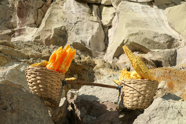 東ジャワ州バニュワンギのイジェン山の火口から採取されたばかりの濃い黄色の硫黄鉱床のバスケット - 写真・画像