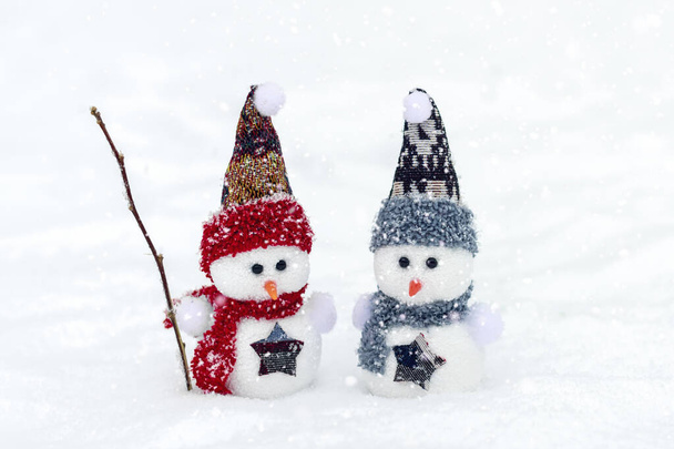 コピースペース付きメリークリスマスと幸せな新年の挨拶カード冬の雪の背景に立って赤、青の帽子とスカーフで幸せな2人の小さな雪だるまクリスマスのおとぎ話こんにちは、 2月のコンセプト - 写真・画像
