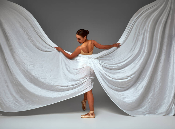 Ballerina Dancing with Silk Fabric, Modern Ballet Dancer in Fluttering Waving Cloth, Pointe Shoes, Gray Background - Foto, Bild