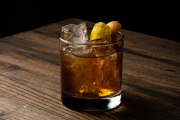 glass of whiskey with ice cubes on wooden background - 写真・画像