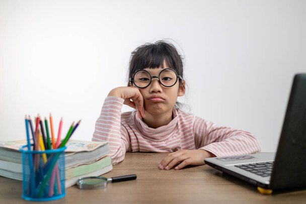 Menina asiática sentada e estudando em casa em um laptop para estudar em casa durante o bloqueio pandêmico Covid-19. Educação online, Homeschooling - Foto, Imagem