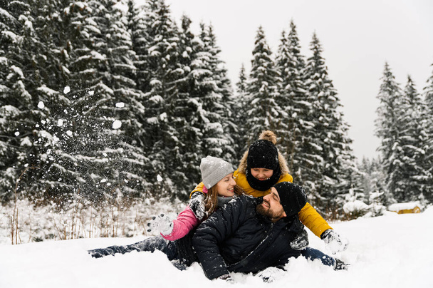 Happy family have fun in winter forest and looking at camera. Mother, father and son playing with snow. Family Christmas concept. Enjoying spending time together - Foto, Imagen