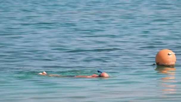 Nierozpoznawalny mężczyzna pływający z maską do nurkowania pod powierzchnią wody morskiej - Materiał filmowy, wideo