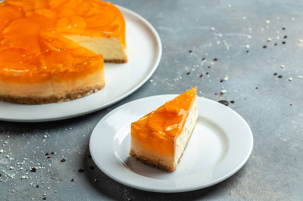 A piece of peach cheesecake on a white ceramic plate. banner, menu, recipe place for text, top view. - Photo, Image