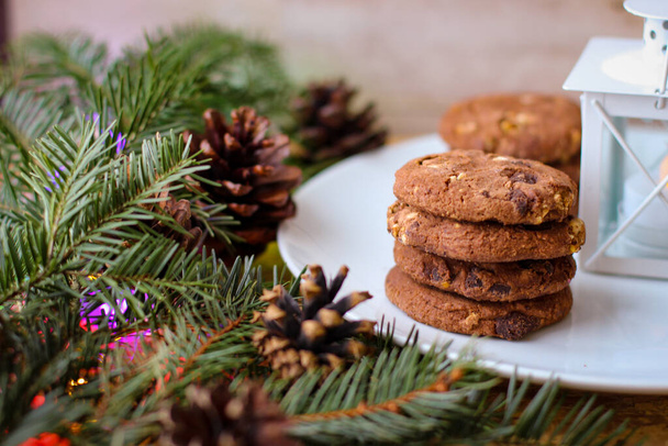 Christmas motifs. Delicious cookies for Santa stands on white plate. In background of spruce branch - Valokuva, kuva