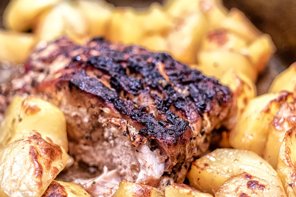 Gebratenes Stück Fleisch mit leicht verbrannter Kruste und Bratkartoffeln zum Garnieren - Foto, Bild