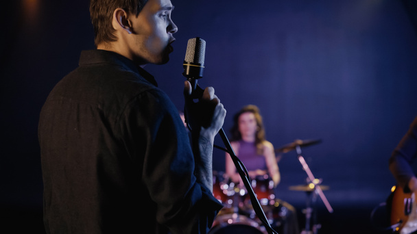 young singer singing in microphone near blurred music band - Photo, Image