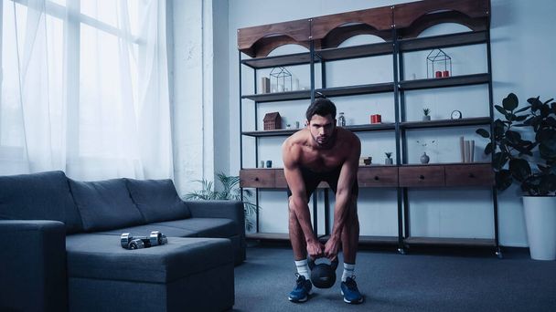 muscular sportsman training with kettlebell at home - Fotoğraf, Görsel