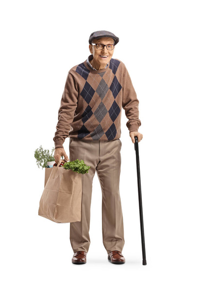 Full length portrait of an old man with a cane carrying grocery bags isolated on white background - Photo, Image
