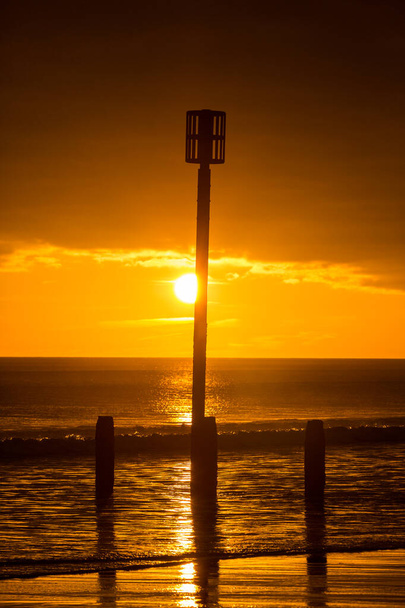 日の出はノーサンバーランドのブライスビーチで一日を始め、セント・メアリーズ灯台までの距離 - 写真・画像