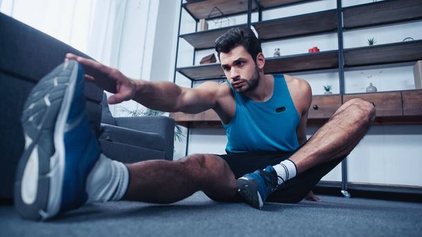 muscular young sportsman stretching at home - Fotoğraf, Görsel