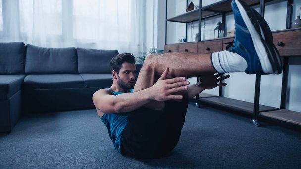 bearded and sportive man working out on floor  - Photo, Image