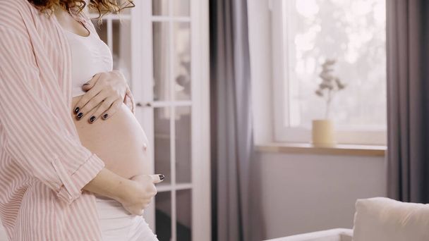 Cropped view of pregnant woman touching belly at home  - Valokuva, kuva