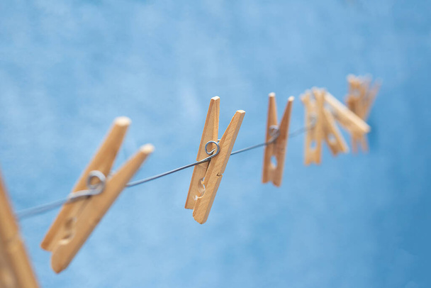 Some wooden clothespins, attached to the clothesline with blue background. - Fotó, kép