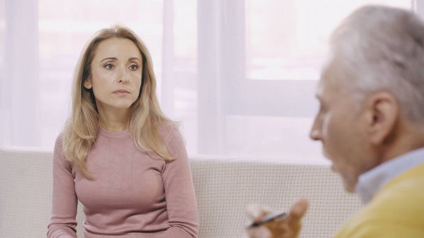 blond vrouw luisteren en kijken naar middelbare leeftijd psychotherapeut - Foto, afbeelding