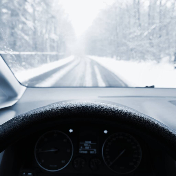 Řídit auto v zimě. Pohled z interiéru auto na zasněžené vozovce očima řidiče. Koncept pro bezpečnost jízdy v zimě. - Fotografie, Obrázek