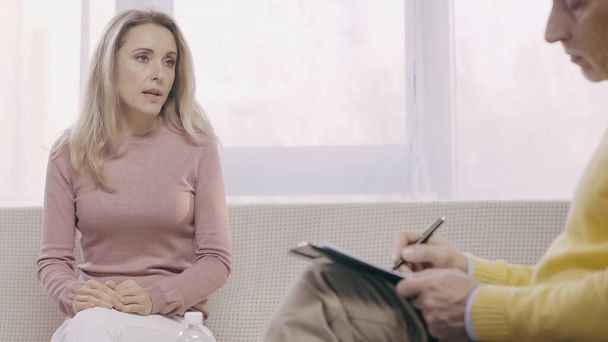 blonde woman talking during consultation with blurred psychologist  - Foto, Imagem