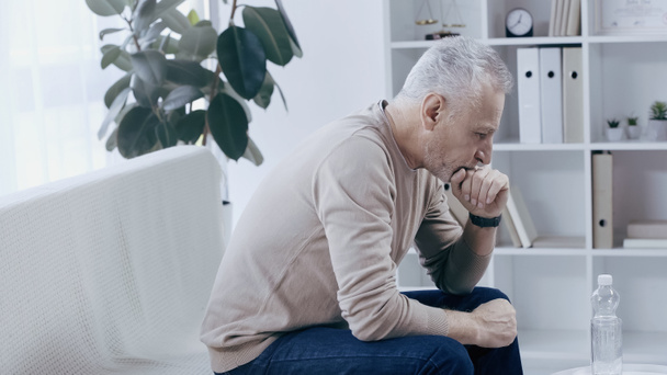 thoughtful middle aged man sitting in consulting room during psychotherapy  - Photo, Image