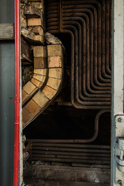 Стара вугільна котельня без однієї стіни з відкритими трубами всередині
 - Фото, зображення