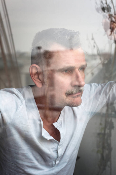 portrait of handsome man in his 50s looking out of window - Foto, Imagem
