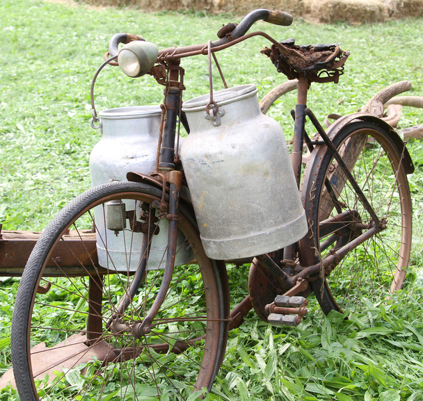 Rostiges altes Fahrrad des Milchmanns mit zwei alten Milchkannen und kaputt  - Foto, Bild